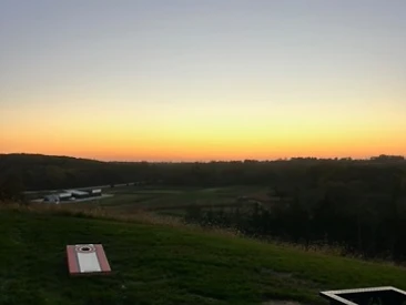 Sunset over the ranch fields with a cornhole board set up on the grass