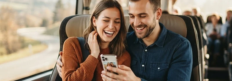 Casal sorrindo olhando o smartphone dentro do ônibus