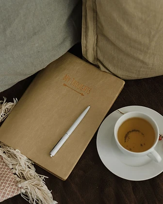 A notebook, pen, and cup of tea