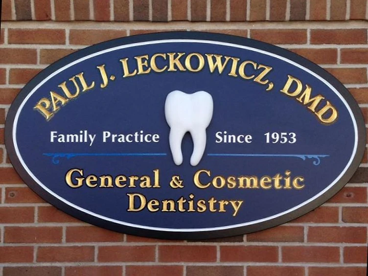 Close-up of 23-karat gold leaf lettering on an oval hand-carved dental sign
