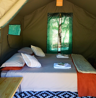Inside a canvas tent: a made-up bed with fresh towels