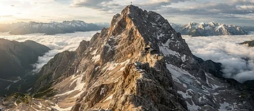 Gipfelgrat der Zugspitze im Alpenlicht mit Blick über Wolken und umliegende Gipfel