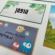 צילום של שלטי דלת מעוצבים מסטודיו שלט לדלת על רקע לבן. השלט העליון הוא שלט לדלת הבית בסגנון נקי עם טקסטורה של עץ לבן ואיורים בוטניים ירוקים, עליו מודפס השם 'הופמן'. מתחתיו מופיע שלט לחדר ילדים צבעוני ושמח על רקע כחול עמוק, המעוטר בדמויות מצוירות של ינשופים חמודים ובכתב יד מעוגל מופיע הכיתוב 'הבית של משפחת אלירז'. השלטים מציגים דוגמה לעיצוב שלטים מותאם אישית שמתאים לכל חלל, בין אם מדובר בשלט כניסה אלגנטי לבית או בשלט צבעוני ומשעשע לחדר הילדים. השלטים עשויים מחומרים איכותיים בגימור מוקפד, המעניקים מראה ייחודי ושלט אישי לכל לקוח.