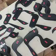 מבט על תהליך הייצור בסטודיו שלט לדלת, הכולל ערימות של שלטים מעוצבים מחומרים איכותיים. התמונה מציגה אלמנטים גרפיים חתוכים בלייזר בצורת תווים מוזיקליים, העשויים מאקריליק שחור מבריק. על גב כל שלט מודבקות רצועות דבק 3M דו-צדדי חזק, המוכנות להרכבה מהירה וקלה. מוצרים אלו משמשים כשלט אישי ייחודי, שניתן לשלב בעיצוב שלטים לחדר ילדים, משרד יצירתי או חלל מוזיקלי בבית. העיצוב המודרני והנקי הופך כל שלט מעוצב מסוג זה לתוספת אסתטית ומרשימה לכל דלת, המשתלבת היטב בקו העיצובי של שלט לדלת הבית או כאלמנט דקורטיבי בחללים מודרניים. השלט מיוצר בהקפדה כדי להעניק פתרון עיצובי מקורי לכל מי שמחפש שלט לכניסה או שלט לחדר עם אמירה אישית.