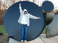 Miguel with arms outstretched against a black sculptural element