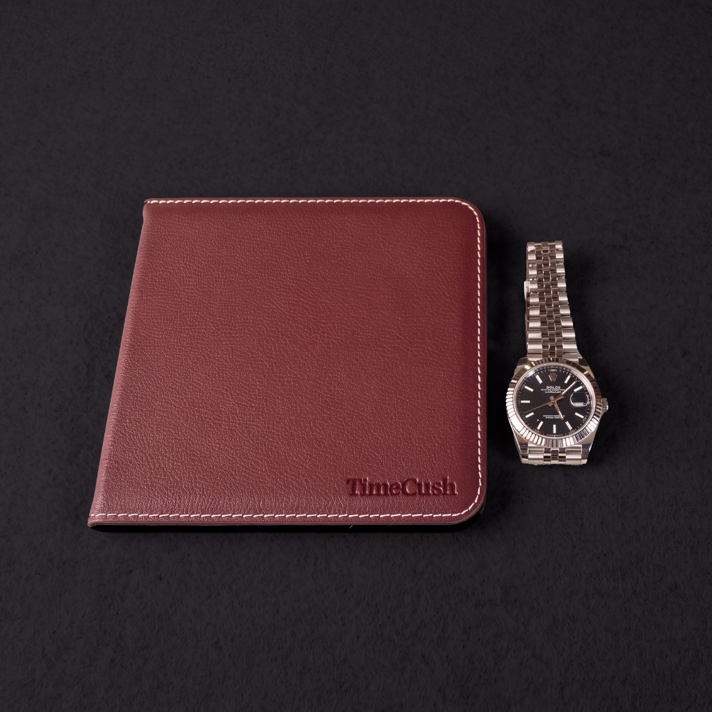 A polished steel watch resting beside a closed TimeCush watch cushion.