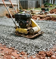 Compacted stone base over red clay at a residential worksite