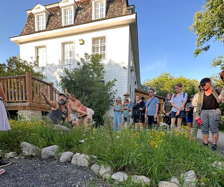 Visitors gathered beside the herb garden on the Hollow Reed monastery grounds