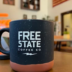Free State Coffee Co mug with the glowing FREE neon sign in the background