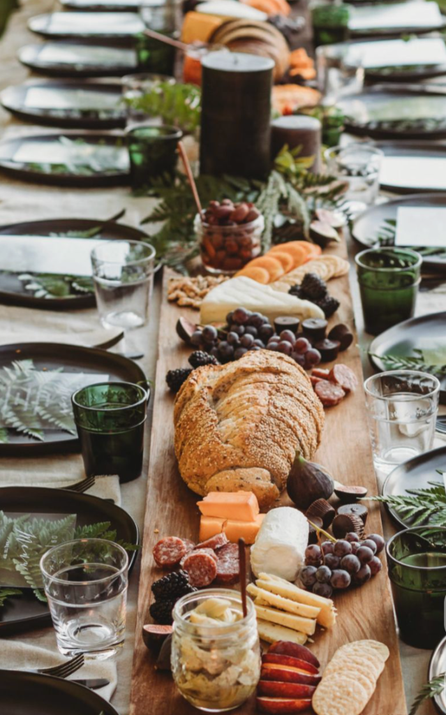 Charcuterie board with ferns and dark glassware