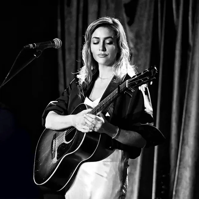 Angel Snow performing on stage with acoustic guitar