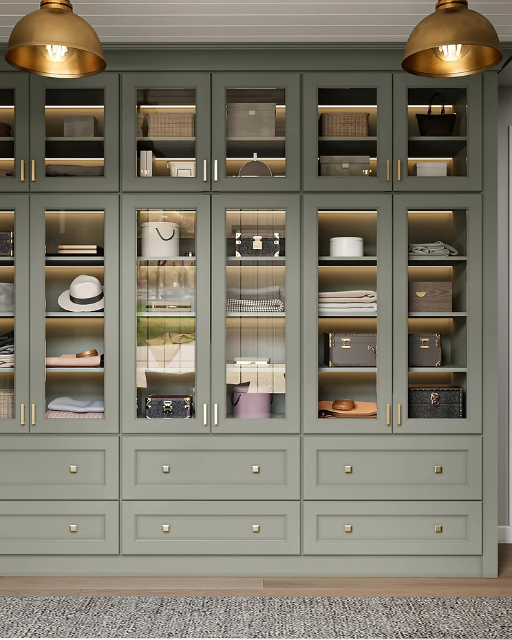 Sage green floor-to-ceiling bathroom storage cabinetry with glass-front display cabinets and brushed gold hardware