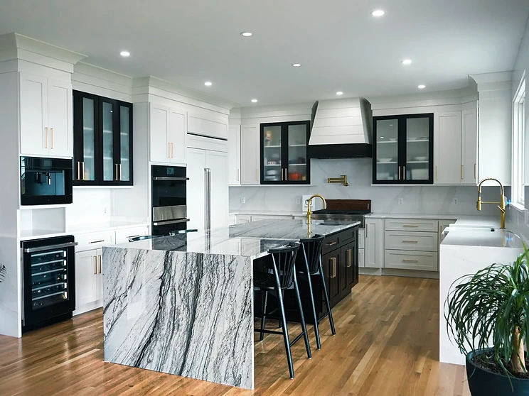 Custom kitchen with white shaker cabinetry, dark island, stone backsplash and copper pendant lighting