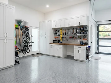 Garage with white shaker cabinetry and slatwall storage