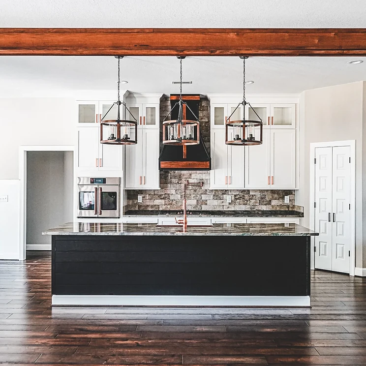 Premium two-tone kitchen with white perimeter cabinetry, dark island, marble countertops and gold hardware