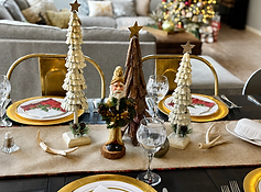 Holiday dining table with burlap runner, white pine tree decorations, and gold-rimmed place settings