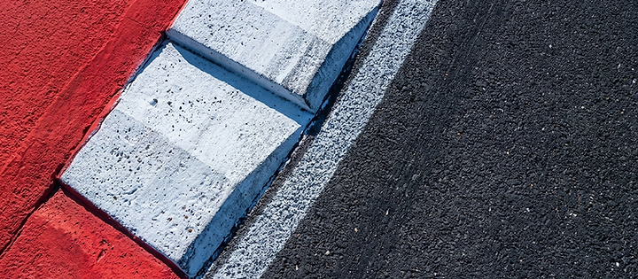 Macro detail of asphalt meeting a concrete curb