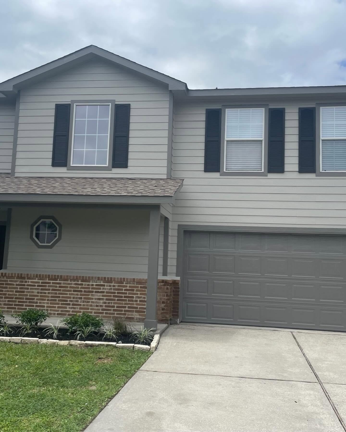 Two-story house with refreshed grey siding and shutters by Arc Painting Solutions in The Woodlands, TX
