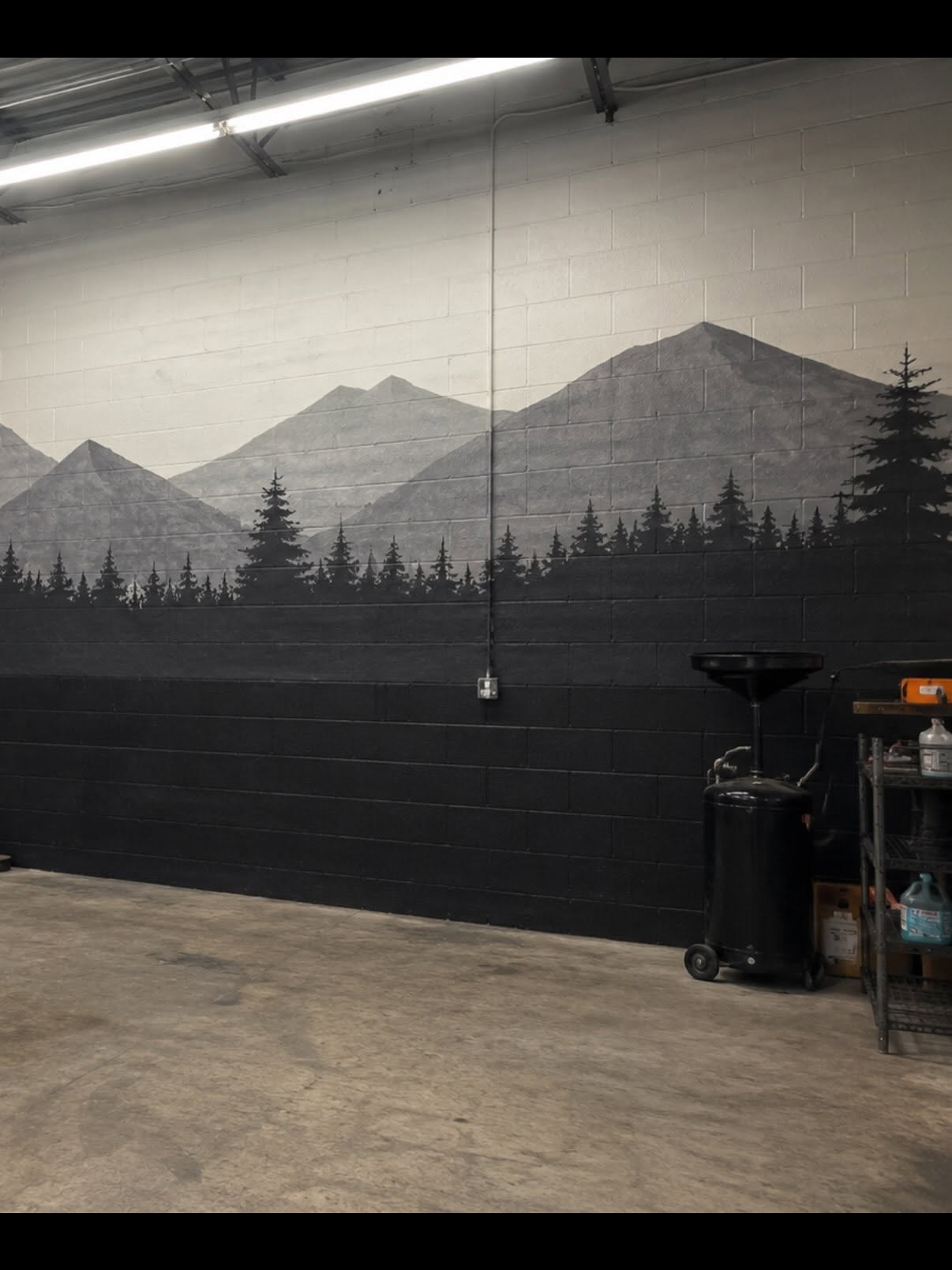 Mountain and pine forest mural hand-painted on a workshop block wall by Arc Painting Solutions in Houston