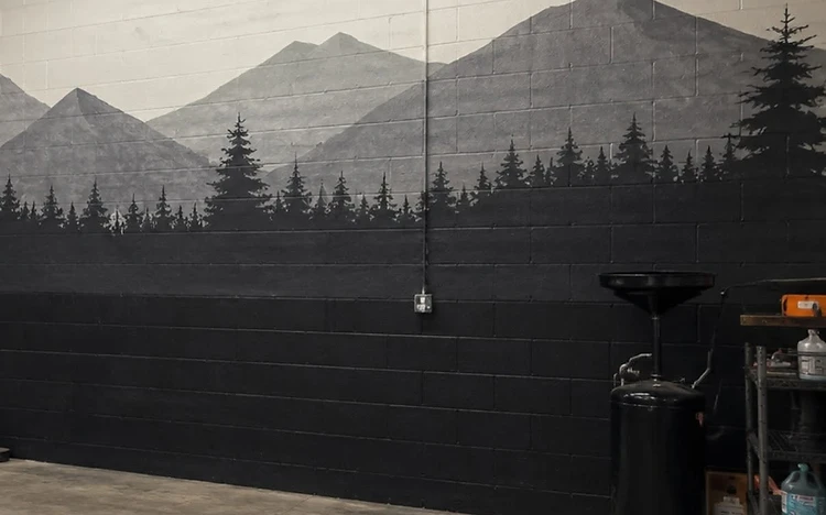 Mountain and pine forest mural hand-painted on a workshop block wall by Arc Painting Solutions in Houston