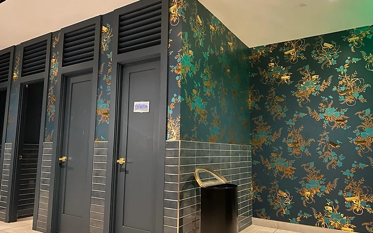 Commercial restroom with gold-pattern wallpaper accent walls by Arc Painting Solutions in Spring, TX