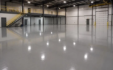 High-gloss industrial epoxy floor with mirror reflections in a warehouse, installed by Arc Painting Solutions