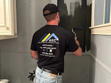 Arc Painting Solutions painter rolling dark paint onto an arched accent niche in a Houston home