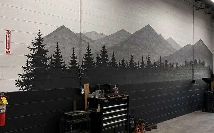 Completed mountain range and forest mural painted on a cinder block wall by Arc Painting Solutions