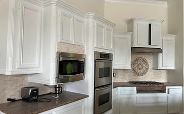 Freshly painted white kitchen cabinets with a decorative tile backsplash by Arc Painting Solutions