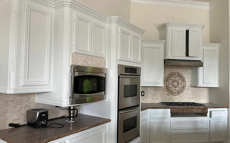 Freshly painted white kitchen cabinets with a decorative tile backsplash by Arc Painting Solutions