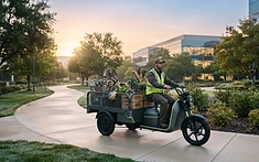 Triciclo elétrico de zeladoria transportando materiais em campus corporativo