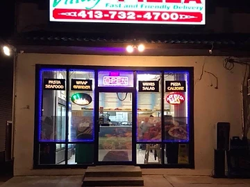 Night storefront with illuminated Village Pizza sign