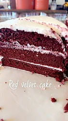 A slice of layered red velvet cake with white frosting