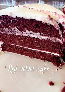 A slice of layered red velvet cake with white frosting