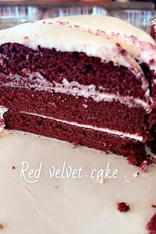 A slice of layered red velvet cake with white frosting