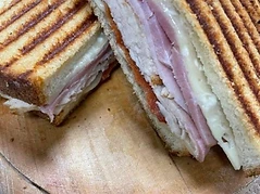 Pressed deli sandwich with sliced meats and melted cheese