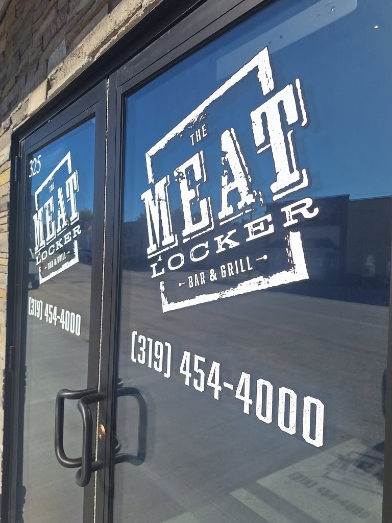 Complete Meat Locker logo artwork and phone number on the restaurant entrance door