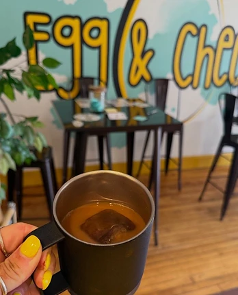 Egg and Cheese dining room with mural, tables, plants, and coffee