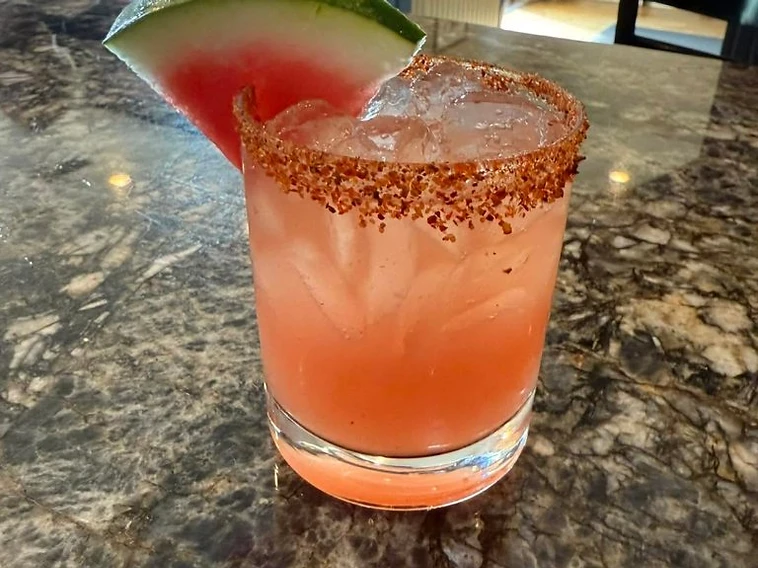 Fruit-garnished drink with dining room tables in the background