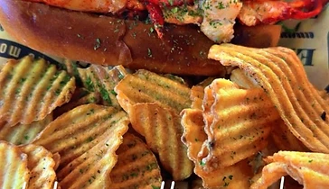 Seasonal lobster roll served with ridged chips and dipping sauce