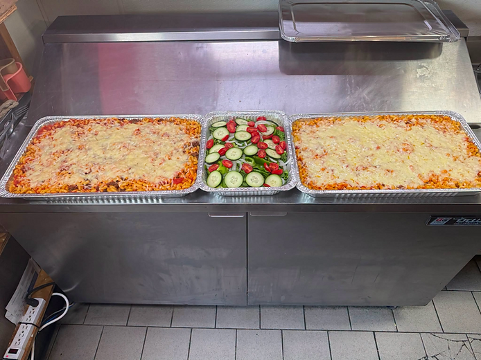 Large prepared catering trays with baked pasta and salad at Jack’s Pleasant Pizza