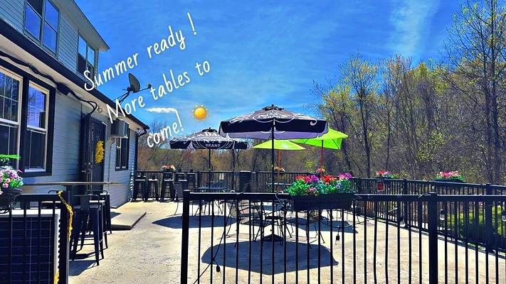 Outdoor patio tables, umbrellas, flowers, and seasonal seating at The Tavern on 66