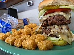 A stacked burger served with crisp tater tots
