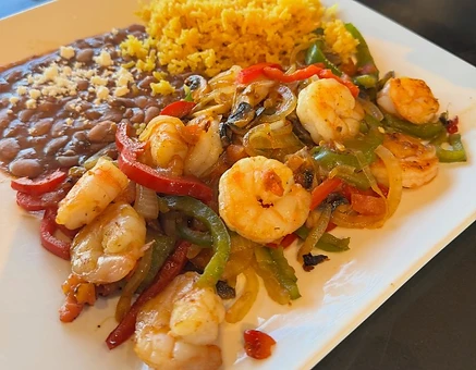 Two plates with shrimp, peppers, onions, rice and beans