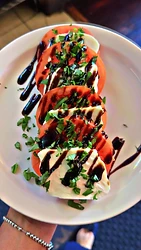 Tomato and mozzarella caprese plate with herbs and dark drizzle