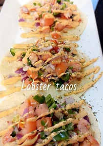 Lobster tacos topped with fresh vegetables and sauce