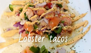Lobster tacos topped with fresh vegetables and sauce