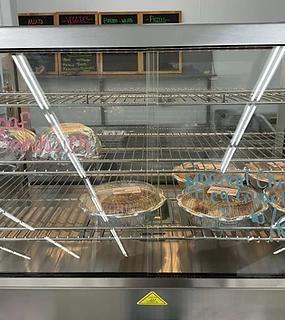 Small deli display case with limited prepared-food selection and handwritten labels