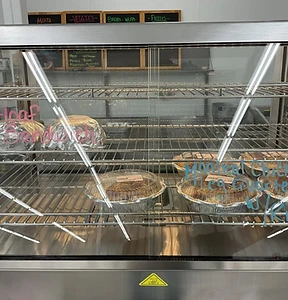 Small deli display case with limited prepared-food selection and handwritten labels