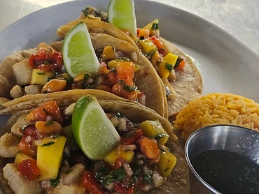 Colorful taco plate with lime wedges, rice, salsa, and bright vegetable garnish